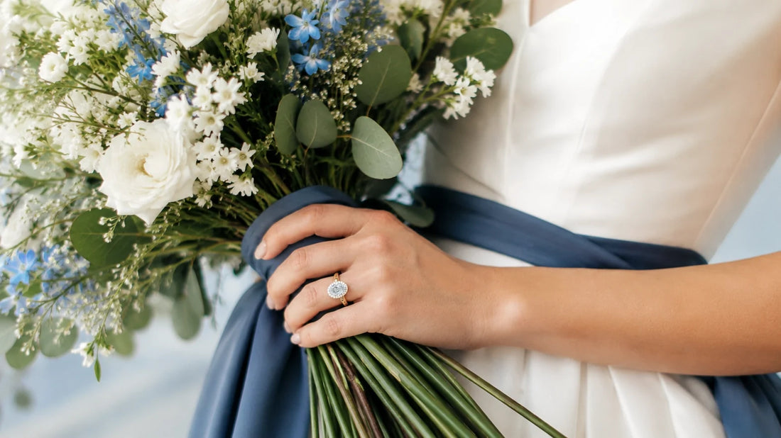 Bride wearing a halo engagement ring with oval ethical diamond holding a bouquet 