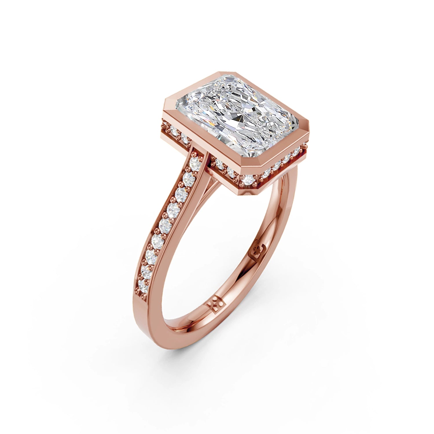 Beautiful pink gold radiant diamond bezel engagement ring with hidden halo, 2 carat centre diamond and a row of bright, white diamonds running down the engagement ring band on white background. Made in Canada. Bague fiançailles à diamants avec halo caché et diamants sur l'anneau sur fond blanc. Fabriquée à Montréal. Style serti clos.
