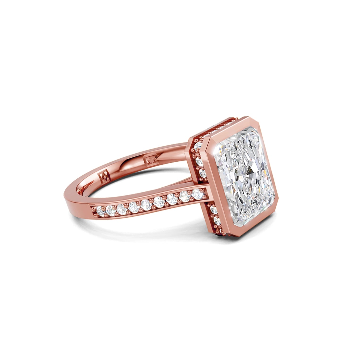 Beautiful pink gold radiant diamond bezel engagement ring with hidden halo, 2 carat centre diamond and a row of bright, white diamonds running down the engagement ring band on white background. Made in Canada. Bague fiançailles à diamants avec halo caché et diamants sur l'anneau sur fond blanc. Fabriquée à Montréal. Style serti clos.