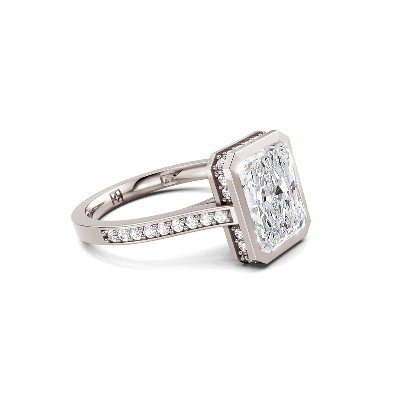 Beautiful white gold or platinum radiant diamond bezel engagement ring with hidden halo, 2 carat centre diamond and a row of bright, white diamonds running down the engagement ring band on white background. Made in Canada. Bague fiançailles à diamants avec halo caché et diamants sur l'anneau sur fond blanc. Fabriquée à Montréal. Style serti clos.