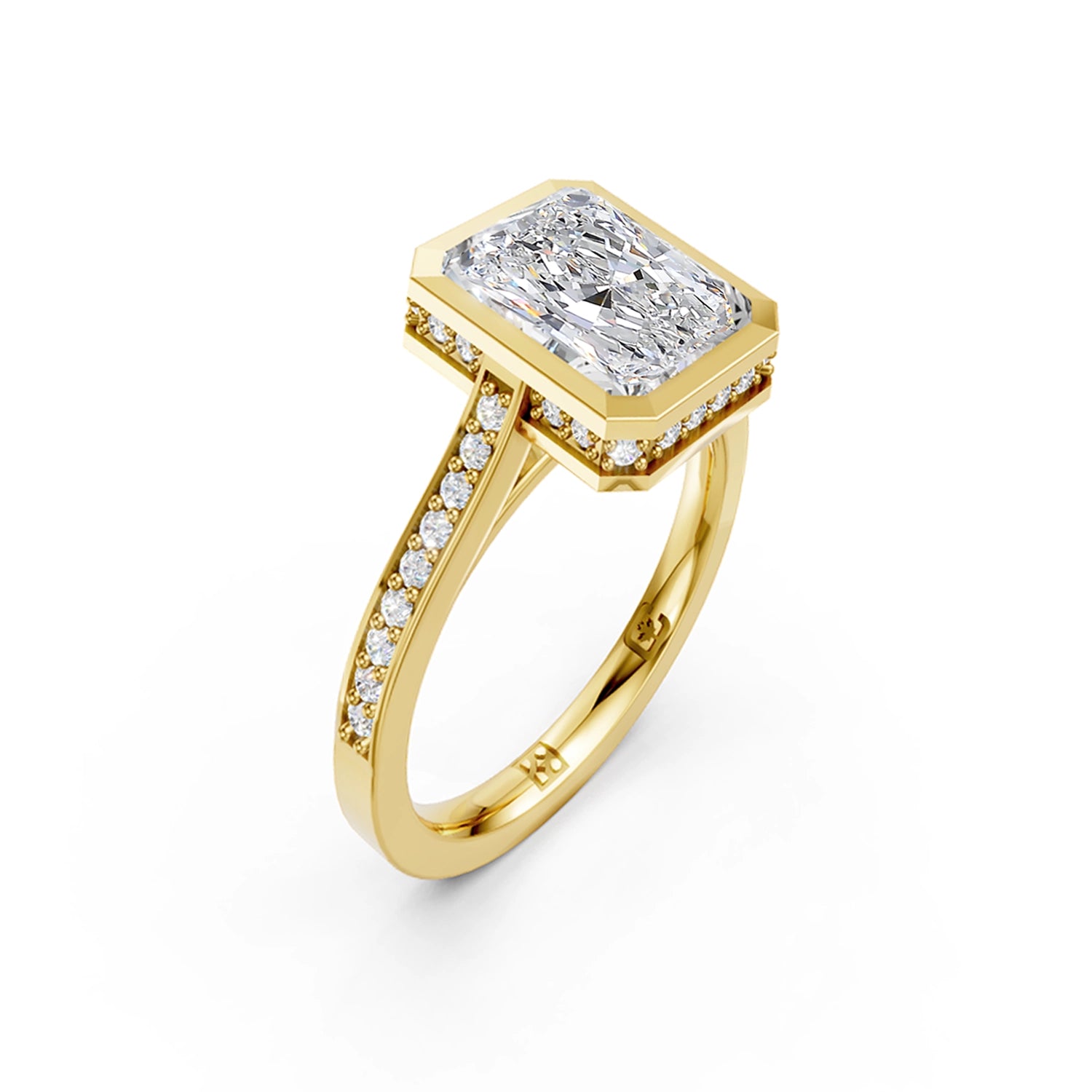 Beautiful yellow gold radiant diamond bezel engagement ring with hidden halo, 2 carat centre diamond and a row of bright, white diamonds running down the engagement ring band on white background. Made in Canada. Bague fiançailles à diamants avec halo caché et diamants sur l'anneau sur fond blanc. Fabriquée à Montréal. Style serti clos.
