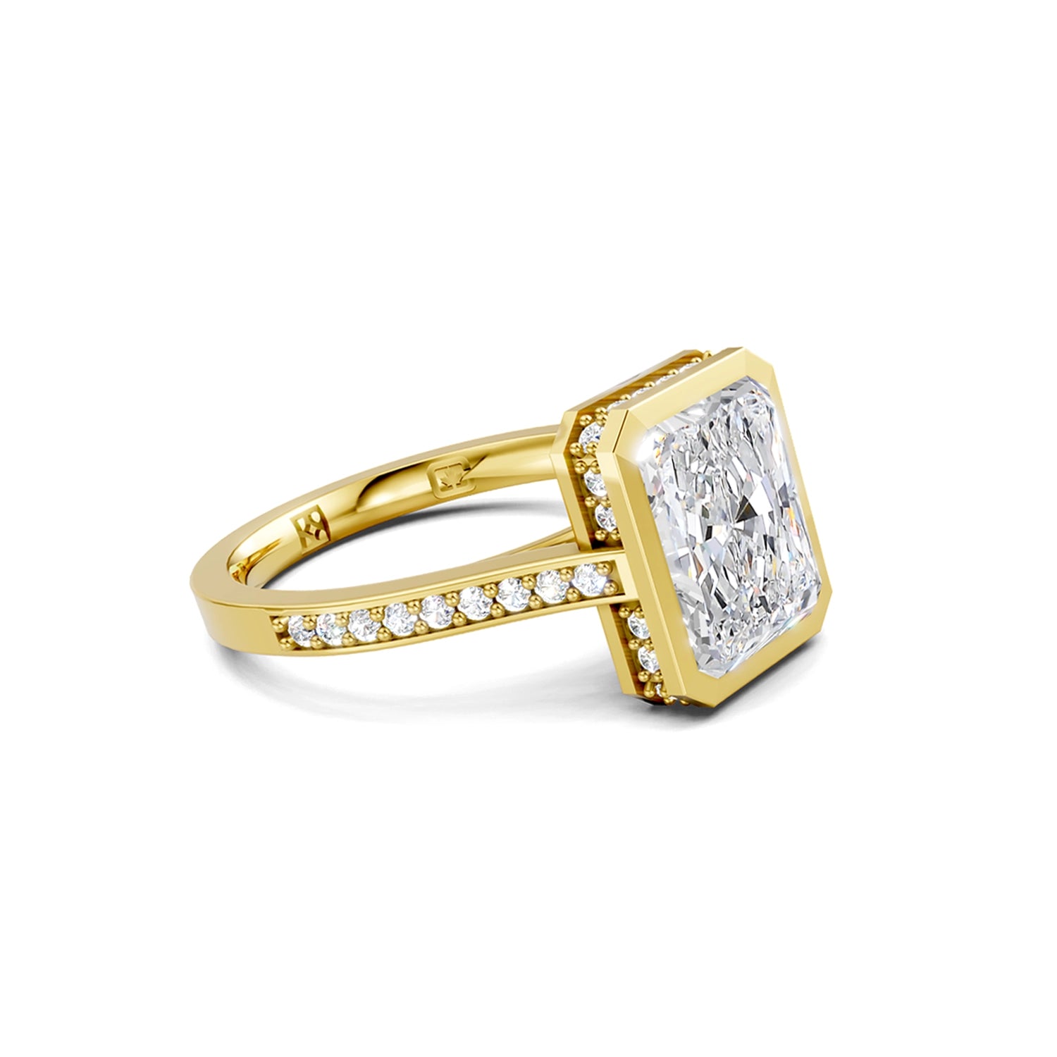 Beautiful yellow gold radiant diamond bezel engagement ring with hidden halo, 2 carat centre diamond and a row of bright, white diamonds running down the engagement ring band on white background. Made in Canada. Bague fiançailles à diamants avec halo caché et diamants sur l'anneau sur fond blanc. Fabriquée à Montréal. Style serti clos.