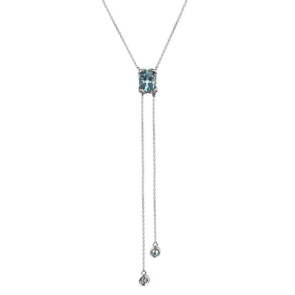 A beautiful lariat necklace with a large aquamarine in a K8 Jewelry exclusive petal setting. Two strands of chain finished with double-set precious stones dangle from the center stone.